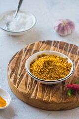 Spicy Svan salt in a white bowl on a wooden board on a light concrete background. Recipes for spices, spicy salt.