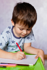 Little boy drawing with color pencils. Boy, drawing a picture for fathers day. Small boy draws at the table.