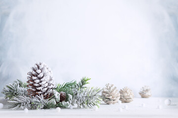 Christmas still life with snowy pine cones, baubles and  fir branches on light background. Winter...