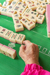 An old active elderly playing mahjong - obrazy, fototapety, plakaty