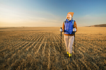 Pretty mature female hiker smiling while looking at beautiful sunset. trekking outdoor, healthy lifestyle, eco tourism.