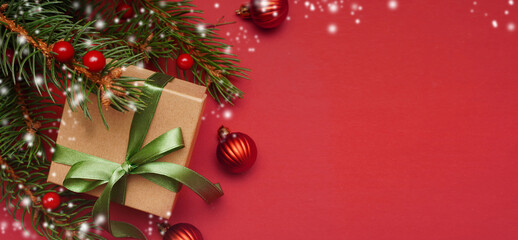  Spruce, fir branches, red berries, gift box on red background. Frame border. Christmas composition. Space for text.