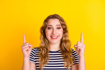 Photo of charming sweet young woman smiling pointing finger empty space isolated yellow color background