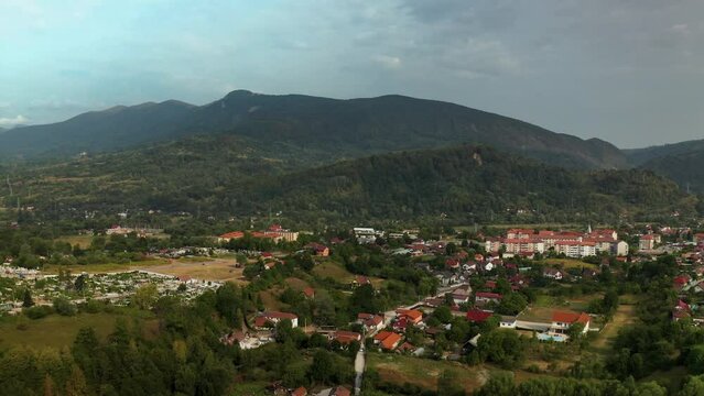 Aerial drone view, over Vulcan, is a small town in the mountains of the Hunedoara region in Romania. The town is situated in the midst of a valley with mountains all around. There are houses dotting t