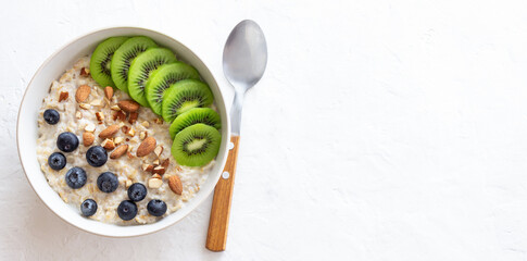 Fototapeta na wymiar Oatmeal with kiwi, blueberries, almonds and honey. Healthy food. Vegetarian food. Breakfast.