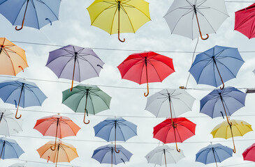 Many colorful umbrellas background. Opened umbrellas in the sky. Urban decoration. Bottom view.