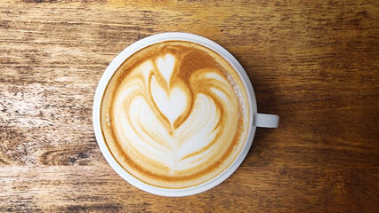 A cup of latte art coffee with tulip shape on old wooden background
