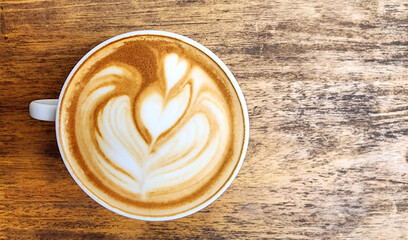 A cup of latte art coffee with tulip shape on old wooden background
