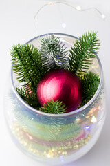 Christmas decoration made of spruce branches and red balls. Christmas decor in a transparent vase on a white background