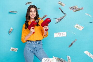 Portrait of excited successful person hold money gun shooting banknotes bills isolated on blue color background © deagreez