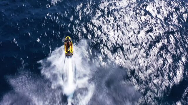 Aerial drone top down video of watercraft showing off in high speed operated by stuntman in deep blue sea