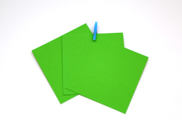 Blue clothespin holding together green note papers.