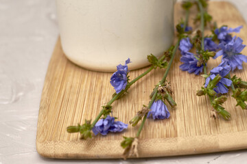 a mug with a drink and chicory flowers on a cutting board