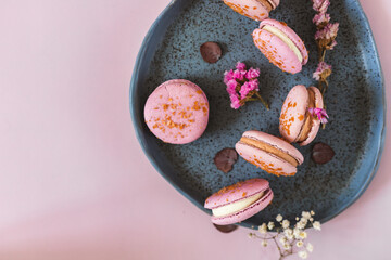 French or Italian macarons with coffee and vanilla filling on pink background. Dessert for tea or coffee break. Food background. Pastel color.