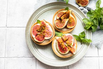 Delicious tartlet with crispy almond-flavored pastry, delicate cheese cream and figs, gray tilled...