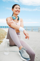 Fototapeta na wymiar Fitness woman, happy and beach exercise while taking break or rest while out running on promenade with a positive mindset, motivation and goal. Happy asian athlete girl runner outdoor for a workout