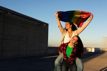 A beautiful lesbian young couple embraces and holds a rainbow flag. LGBT community