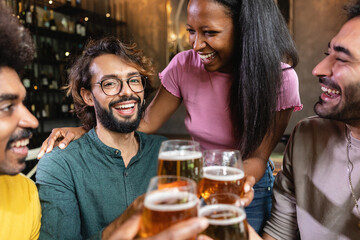 Multiracial group of young best friends talking and having fun drinking at brewery bar - Multiethnic people enjoying happy hours together at irish pub toasting craft beer