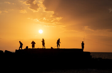 Fototapeta na wymiar people silhouettes and sunset on the beach