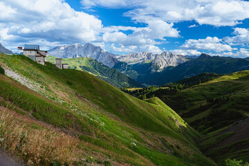Obraz premium The view of the Dolomites seen from the Sella pass with the lights of the sunset, one of the most famous places in the Alps, near the town of Canazei, Italy - August 2022.