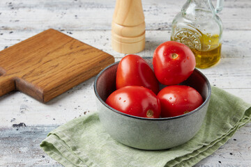 Juicy tomatoes in a gray clay plate on a wooden table, place for text