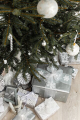 White and silver gift boxes with bows under the Christmas tree and snow, Merry Christmas and Happy New Year