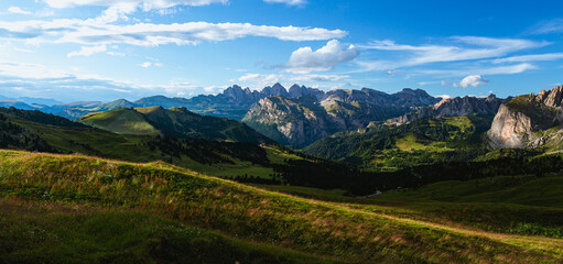 Fototapeta na wymiar The view of the Dolomites seen from the Sella pass with the lights of the sunset, one of the most famous places in the Alps, near the town of Canazei, Italy - August 2022.