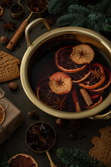 Christmas hot alcoholic drink mulled wine in a pan with citruses, aromatic spices, cinnamon and dried fruits among the spruce branches