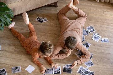 Children look at photos on the floor. Brother and sister at home looking at photos