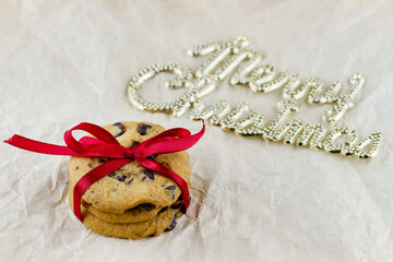 Christmas composition. Chocolate chip cookies decorated red bow on crumpled paper with 3d text (Merry Christmas) background