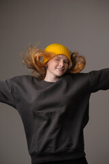 young girl model in yellow cap and gray coat isolated on gray background. Product photo mockup for fashion brands and marketplaces, woolen cap, turkish textiles.