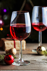 Glasses of red wine with gift box and color balls on wooden table. Christmas (New Year) decoration composition