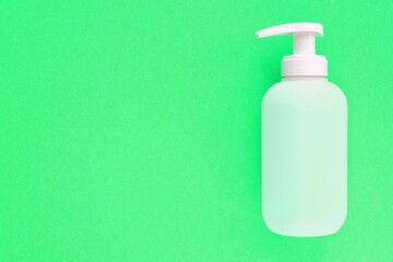 White unbranded plastic dispenser pump bottle on green background with copy space for text. Cosmetic package mockup, liquid soap flacon, hand sanitizer without label, shampoo organic spa, shower gel
