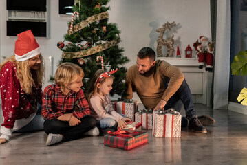 Obraz na płótnie Canvas Happy family of four sharing Christmas gifts