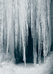 Large icicles hanging down. Icicles at the entrance to the cave. Frozen flowing water