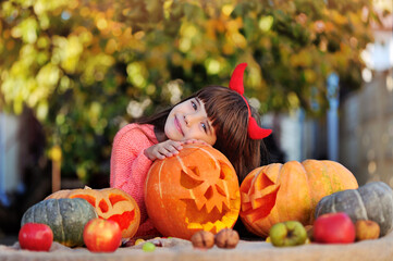 Girl wearing devil horns hugging carved Halloween pumpkin