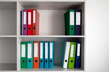 Office shelves with colorful folders. Folders on the shelves in the office closet. - obrazy, fototapety, plakaty