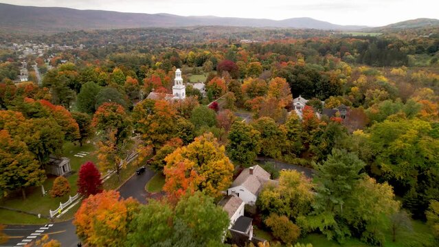 aerial high push over treetops toward church in bennington vermont in autumn