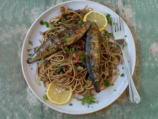 Pan fried Sardines with whole wheat pasta cooked with olive oil, garlic, peppers and parsley on a...