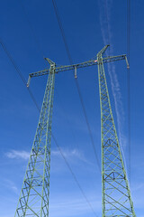 Pylons for high voltage transmission line. View from underside to masts with glass disk insulators, sky and clouds.