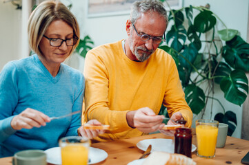 Senior couple eating breakfast at home and spending morning together