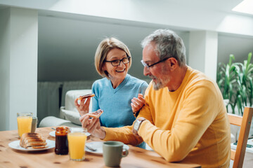 Senior couple eating breakfast at home and spending morning together