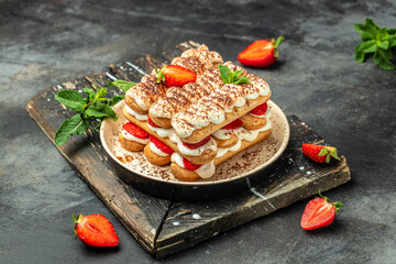 homemade tiramisu cake with fresh strawberry, mascarpone and mint. Tiramisu portion on plate on dark background. Delicious no bake tiramisu