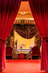 Red velvet curtains that reveal the interior of the theater in the background.