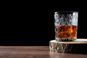 Scotch whiskey glass on wooden table and black background