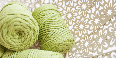 Handmade macrame braiding and cotton threads in basket on white background. Cotton macrame cords and ropes against wire basket. Good image for macrame and handicrafts banners and advertisement.