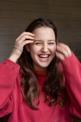 young beautiful girl with long hair in a red pullover laughs, the concept of love, joy, mental health