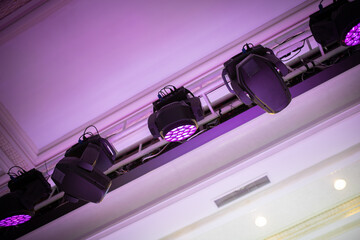 Light heads beam and fill hang on a truss above the ceiling in event hall.