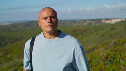 Athletic man walking outdoors with yoga mat. Focused tourist going natural park