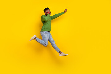 Naklejka na ściany i meble Full length body size view of handsome trendy cheery guy jumping talking on phone isolated on vivid yellow color background